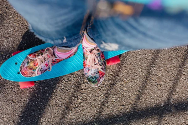 Close up van voeten op blauwe cent skate bord met pinl wielen. — Stockfoto