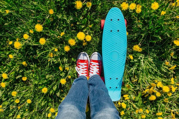 Яркий и красочный скейтборд и женские ноги в кроссовках — стоковое фото