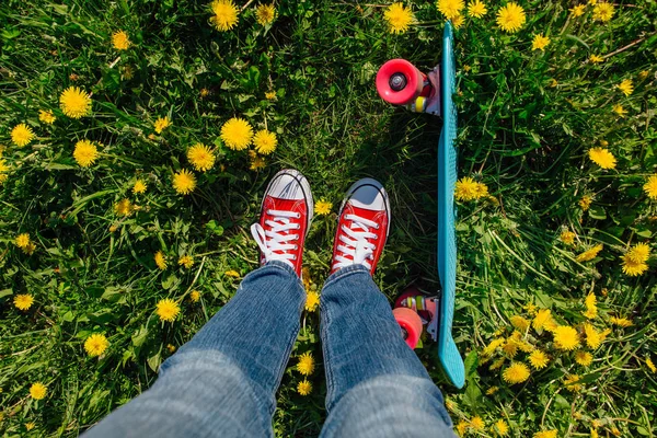 Jasné a barevné skateboard a ženské nohy v teniskách — Stock fotografie
