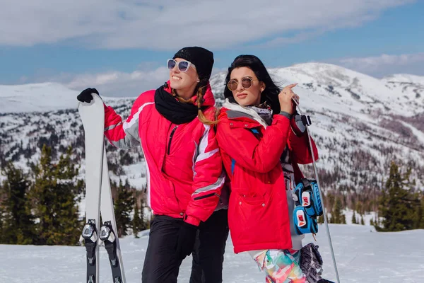 Dos youn mujeres con esquí y snowboard —  Fotos de Stock