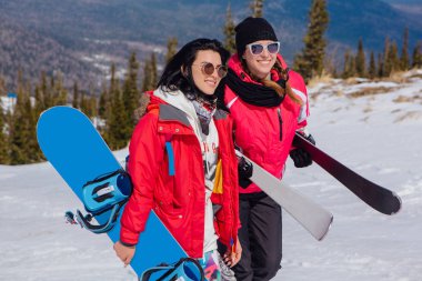 Kayak ve snowboard olan iki genç kadın