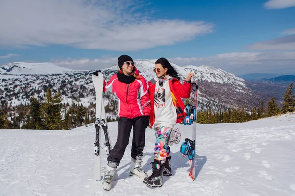 Dos youn mujeres con esquí y snowboard — Foto de Stock