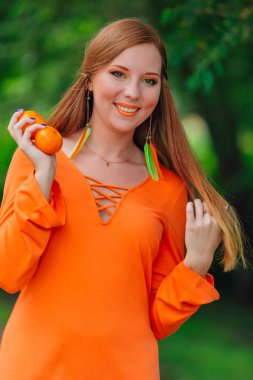 Yaz yeşil park sulu lezzetli mandalina ile oldukça Kızıl saçlı kadın portresi.
