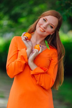 Yaz yeşil park sulu lezzetli mandalina ile oldukça Kızıl saçlı kadın portresi.