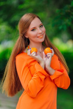 Yaz yeşil park sulu lezzetli mandalina ile oldukça Kızıl saçlı kadın portresi.