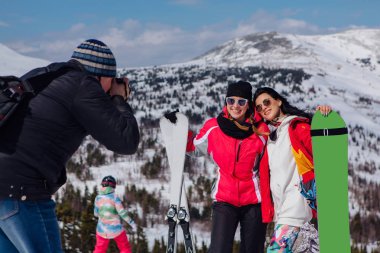 Fotoğrafçı resmi kayak ve snowboard olan iki genç kadın dağlarda kayak tatil alır