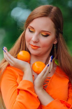 Yaz yeşil park sulu lezzetli mandalina ile oldukça Kızıl saçlı kadın portresi.