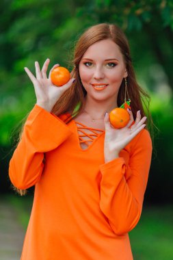 Yaz yeşil park sulu lezzetli mandalina ile oldukça Kızıl saçlı kadın portresi.