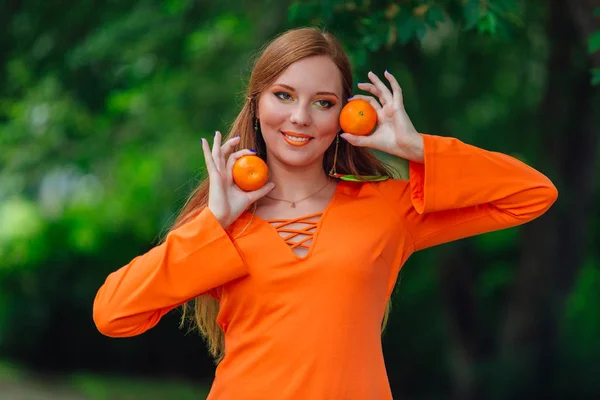 Portret van vrij rood haar vrouw met sappige heerlijke mandarijnen in zomer groen park. — Stockfoto