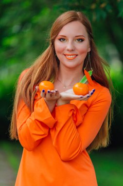 Yaz yeşil park sulu lezzetli mandalina ile oldukça Kızıl saçlı kadın portresi.