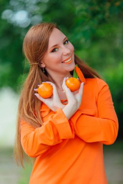 Yaz yeşil park sulu lezzetli mandalina ile oldukça Kızıl saçlı kadın portresi.