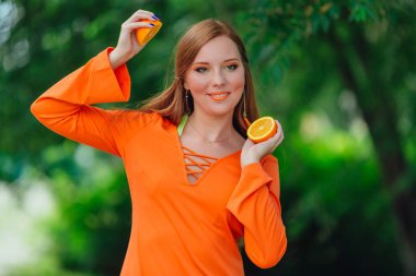 Kırmızı saçlı kadın portresi tamamlayan bir yaz yeşil park sulu lezzetli portakal ile.