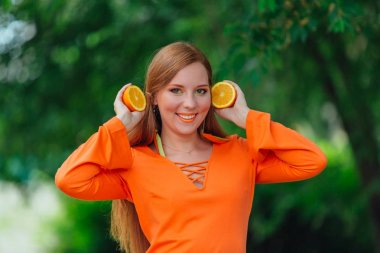 Kırmızı saçlı kadın portresi tamamlayan bir yaz yeşil park sulu lezzetli portakal ile.