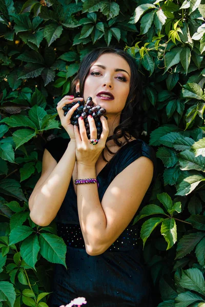 Retrato de joven morena sexy con uvas negras . — Foto de Stock