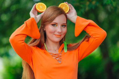 Kırmızı saçlı kadın portresi tamamlayan bir yaz yeşil park sulu lezzetli portakal ile.