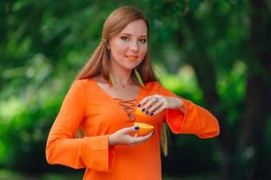 Kırmızı saçlı kadın portresi tamamlayan bir yaz yeşil park sulu lezzetli portakal ile.