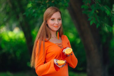 Kırmızı saçlı kadın portresi tamamlayan bir yaz yeşil park sulu lezzetli portakal ile.