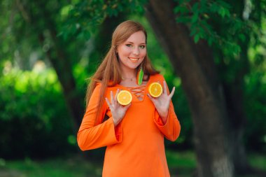 Kırmızı saçlı kadın portresi tamamlayan bir yaz yeşil park sulu lezzetli portakal ile.