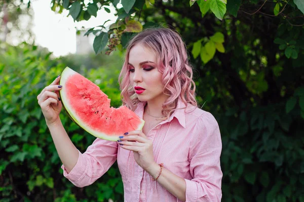 Hermosa joven con cabello rosa disfrutando de la sandía — Foto de Stock