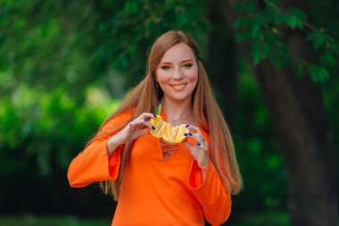 Sulu lezzetli turuncu yaz yeşil park adlı tutan güzel kızıl saçlı kadın portresi.