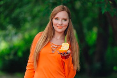 Sulu lezzetli turuncu yaz yeşil park adlı tutan güzel kızıl saçlı kadın portresi.