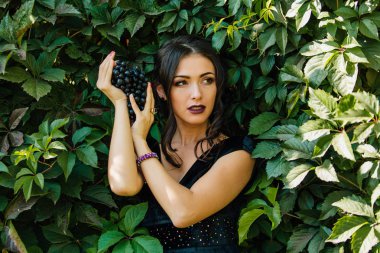 Siyah üzüm ile siyah elbiseli genç seksi esmer portresi. .