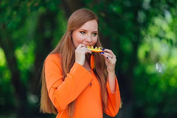 Porträt einer hübschen Frau mit rotem Haar und saftigen Orangen im sommergrünen Park. — Stockfoto