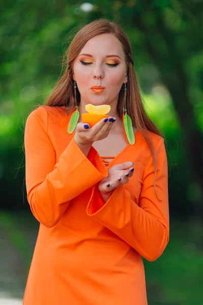 Portrait of pretty red hair woman with juicy delicious orange at summer green park. — Stock Photo, Image