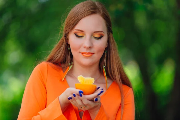 Portret van vrij rood haar vrouw met sappige heerlijke oranje in zomer groen park. — Stockfoto