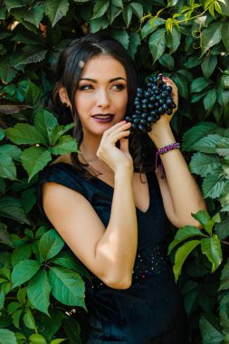 Siyah üzüm ile siyah elbiseli genç seksi esmer portresi. .