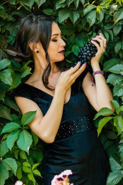 Siyah üzüm ile siyah elbiseli genç seksi esmer portresi. .