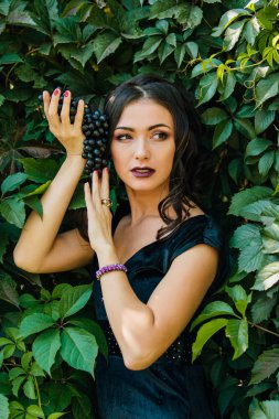 Siyah üzüm ile siyah elbiseli genç seksi esmer portresi. .