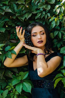 Siyah üzüm ile siyah elbiseli genç seksi esmer portresi. .