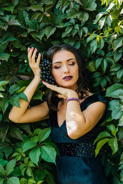 Genç seksi esmer siyah üzüm ile portresi.