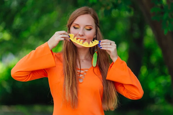 Retrato de bonita mujer pelirroja con jugosa naranja deliciosa en el parque verde de verano . — Foto de Stock