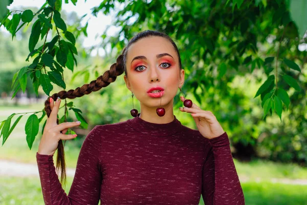 Mulher bonita com trança longa e brincos de cereja naturais . — Fotografia de Stock