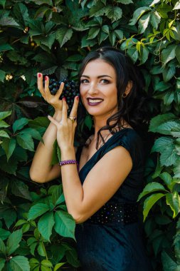 Siyah üzüm ile siyah elbiseli genç seksi esmer portresi. .