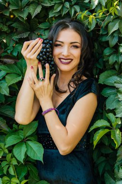Siyah üzüm ile siyah elbiseli genç seksi esmer portresi. .