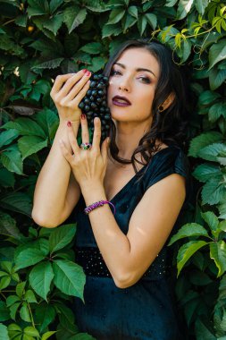 Siyah üzüm ile siyah elbiseli genç seksi esmer portresi. .