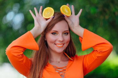 Yaz yeşil park adlı iki sulu lezzetli portakal dilim tutan güzel kızıl saçlı kadın portresi.
