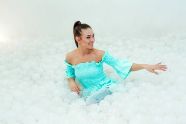 Beyaz plastik toplar yetişkin için kuru havuzda çevrili mutlu güzel kadın bırakır.