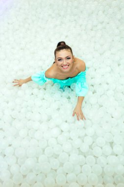 Mutlu güzel kadın yetişkin için kuru havuzda beyaz plastik toplar ile çevrili bırakır. Kopya alanı.