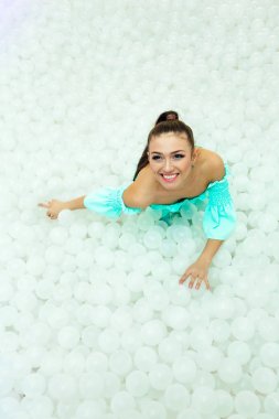 Beyaz plastik toplar yetişkin için kuru havuzda çevrili mutlu güzel kadın bırakır.