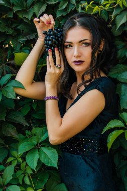 Siyah üzüm ile siyah elbiseli genç seksi esmer portresi. .
