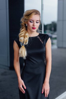 Uzun Abiye blong saçlı çekici Bayan ayna windows ile bina yanında duruyor