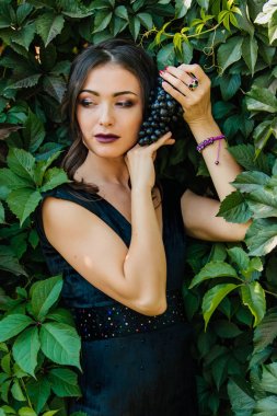 Siyah üzüm ile siyah elbiseli genç seksi esmer portresi. .