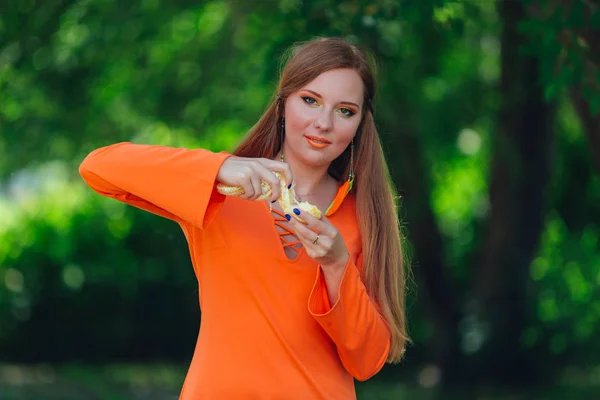 Porträt einer hübschen Frau mit rotem Haar und saftigen Orangen im sommergrünen Park. — Stockfoto