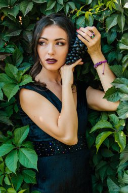 Siyah üzüm ile siyah elbiseli genç seksi esmer portresi. .