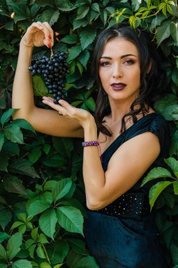 Siyah üzüm ile siyah elbiseli genç seksi esmer portresi. .