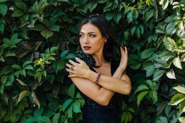 Siyah üzüm ile siyah elbiseli genç seksi esmer portresi. Kopya alanı.